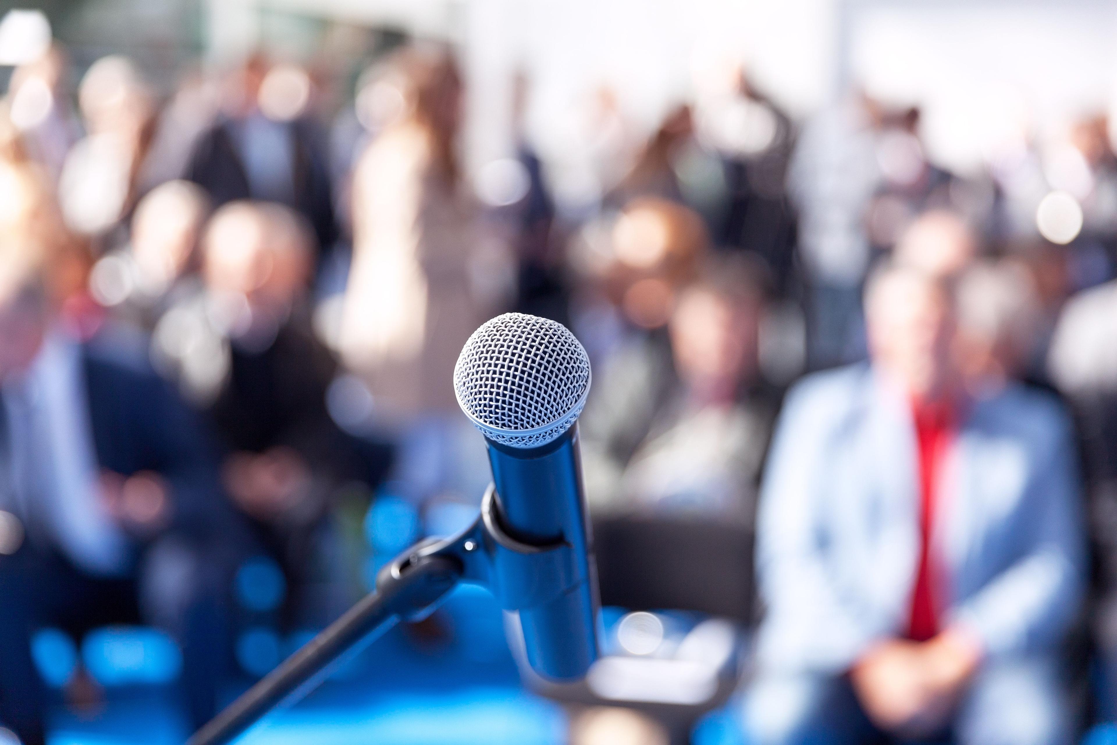 Up close view of microphone with blurred audience background