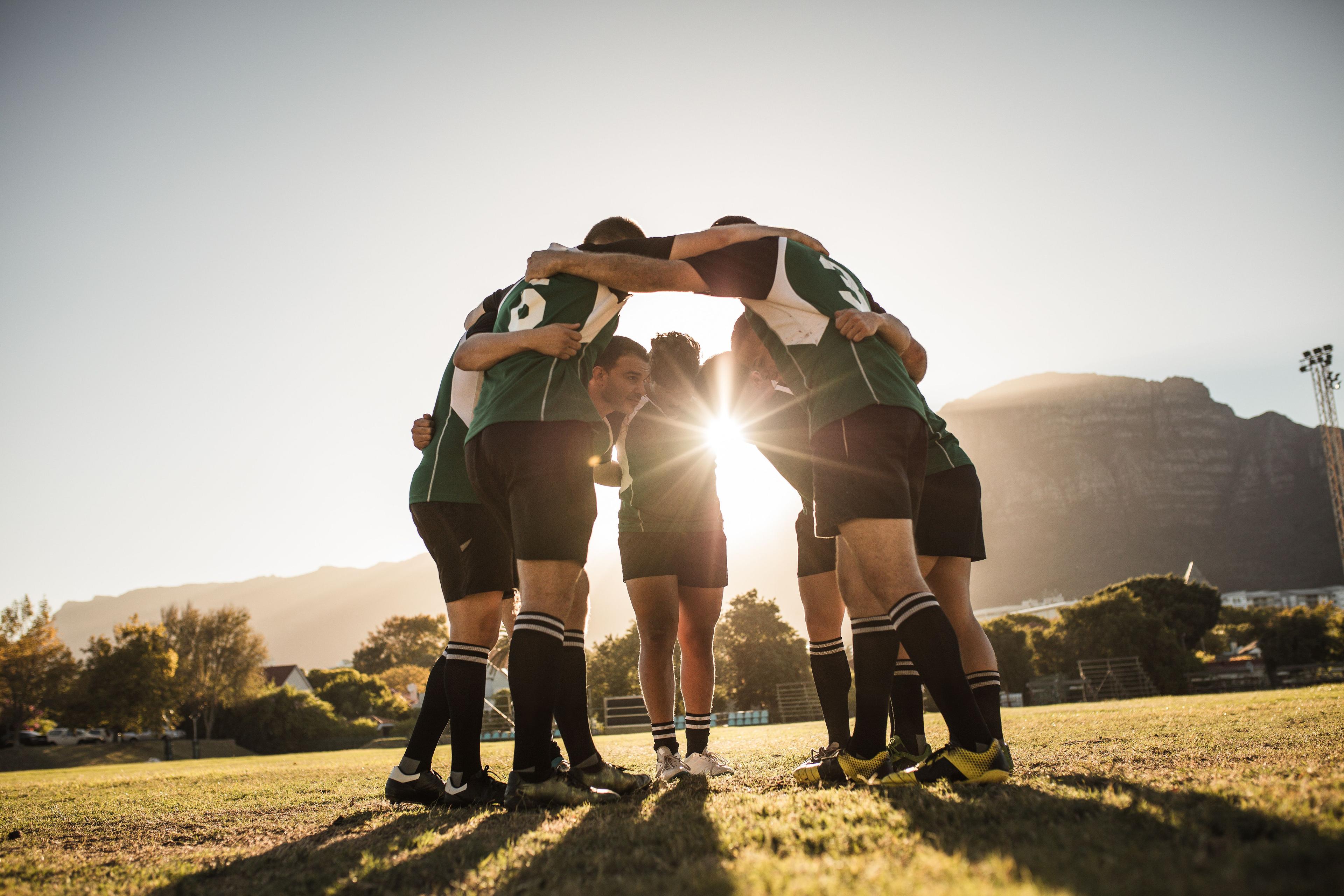 Rugby players huddling on field